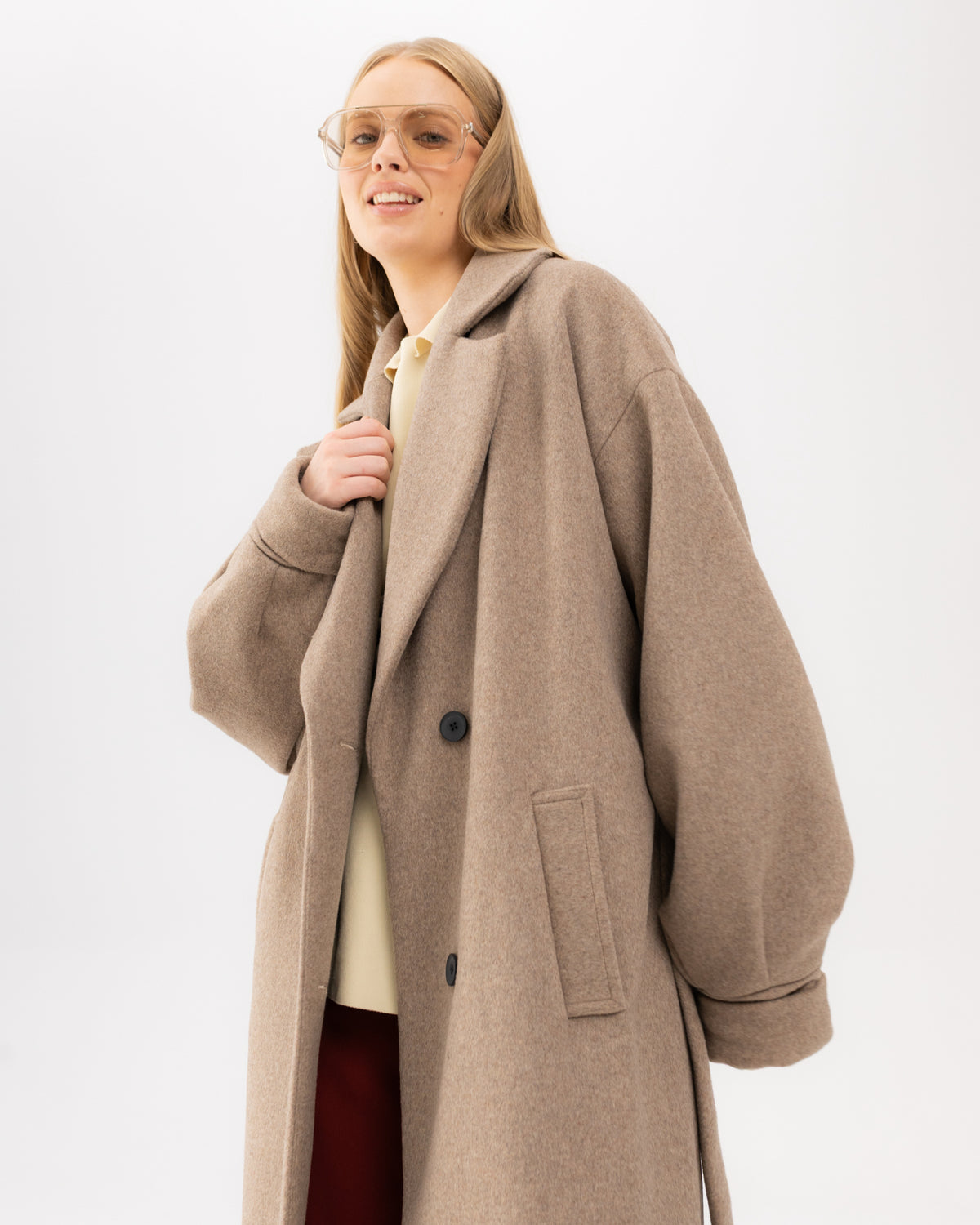 Beżowy płaszcz oversize mokka na modelce, ujęcie do ud