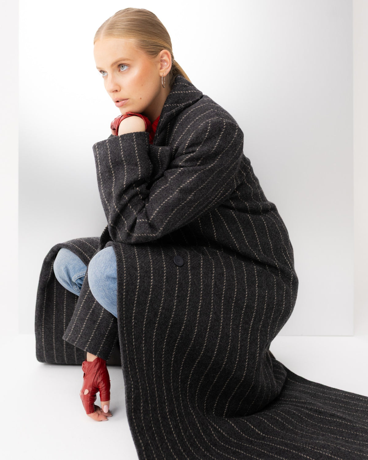 Grafitowy płaszcz wide one size w prążki na modelce w przysiadzie