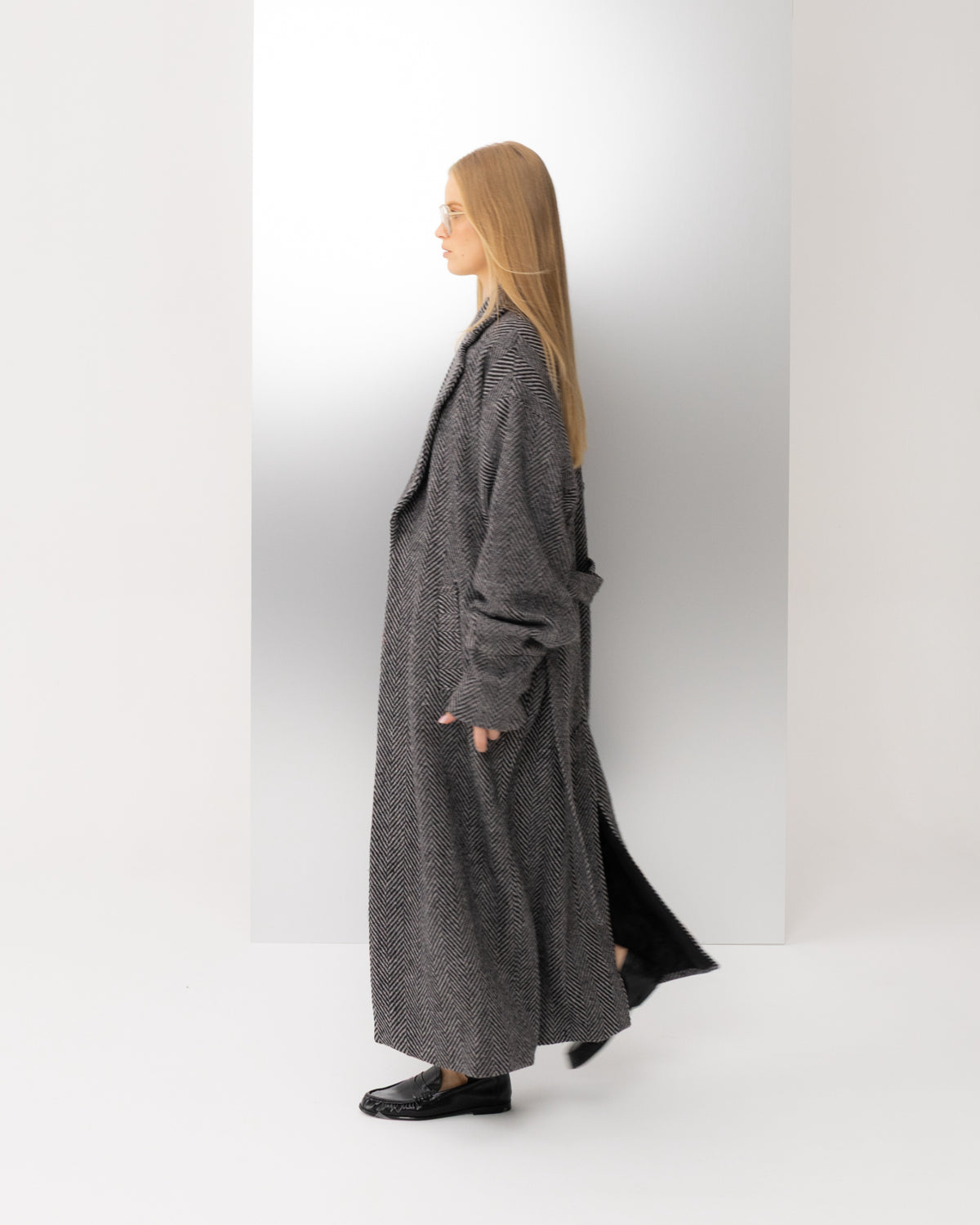 Płaszcz oversize w czarno-białą jodełkę w ruchu, cała sylwetka z boku