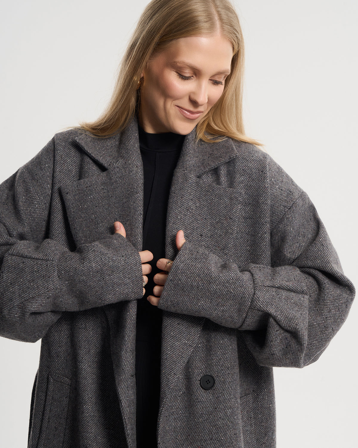 Szary płaszcz oversize w paseczki na modelce, ujęcie do pasa